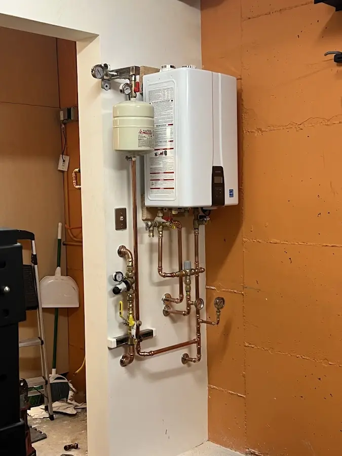 Plumbing technician inspecting water heater connections in Farmers Branch